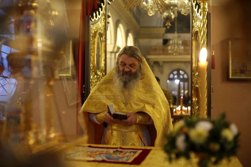 Священник протоиерей Сергий Баранов в богато украшенном желтом одеянии читает книгу в гродненском Свято-Покровском кафедральном соборе