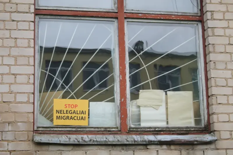 Окно на первом этаже здания, где изначально планировали обустроить лагерь для беженцев. Надпись на наклейке: “Стоп нелегальной миграции”. Фото: Hrodna.life